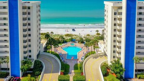 A hotel with a pool, beach view, and multiple floors.