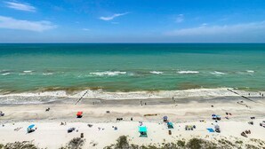 A beach with clear skies, calm waters, and people sunbathing.