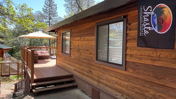 Een houten hut met terras, schotelantenne en een bordje voor Shasta Lake Resort & Spa.