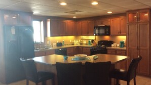 A kitchen with wooden cabinets, a microwave, a stove, and a dining area with four chairs.