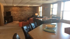 A dining area with a brick wall, a fireplace, and a television.
