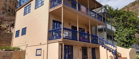 Un edificio de varios pisos con balcones, una escalera y mesas al aire libre.
