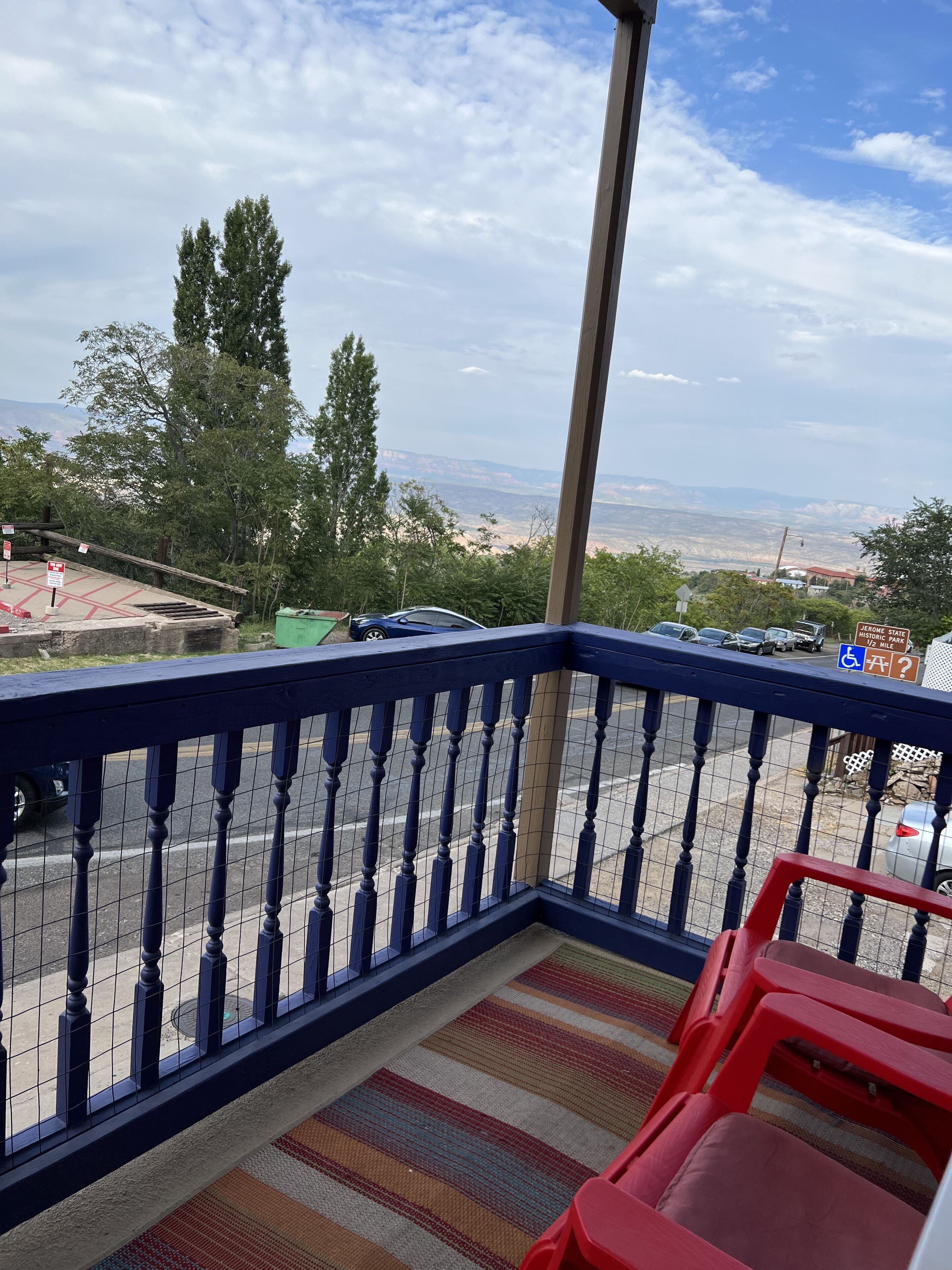 A balcony with a view of a parking lot and distant mountains.