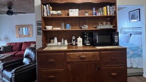 Ein Holzkabinett mit einem ‚Wi-Fi‘-Schild, einer Kaffeemaschine und einer Mikrowelle darauf.
