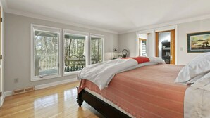A bedroom with a large bed, a window, a door, and a view of the outdoors. - Waterfront Paradise with Pool & Hot Tub plus 4 King Beds & 4 Full baths (Lexington Park)