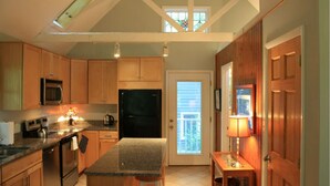 A kitchen with wooden cabinets, a granite countertop, a refrigerator, a stove, and a window with a view. - Waterfront Paradise with Pool & Hot Tub plus 4 King Beds & 4 Full baths (Lexington Park)