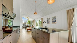 Une cuisine spacieuse dotée d’un îlot central, de meubles en bois et de luminaires suspendus.