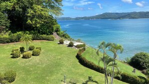 A landscaped garden with a view of the sea and distant hills.