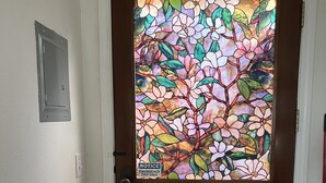Una puerta de madera con un vitral que representa flores y hojas.