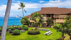 A hotel with a pool, palm trees, and a view of the ocean. - 🏖️SPECTACULAR - OCEANFRONT - GREAT LOCATION!!!🏖️ (Kailua-Kona)