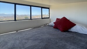 A bedroom with a large window, a bed with grey and white bedding, and a red pillow. - Wine country In Valle de Guadalupe (Valle de Guadalupe)