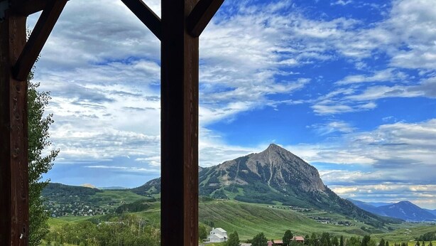 A hot tub with a mountain view, red chairs, and a wooden structure. - Hot Tub with Amazing Views- 7min to town/resort (Crested Butte)
