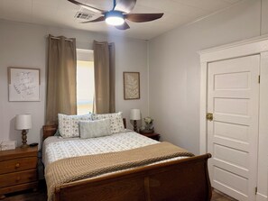 Una camera da letto con un letto, comodini, una ventola a soffitto e una porta.