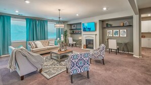 A living room with a sofa, two armchairs, a coffee table, a fireplace, and a TV mounted on the wall. - 1000MBPS Wifi★One Story Luxury 5 Bedrooms Model Home (Jurupa Valley)