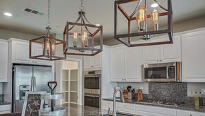 A modern kitchen with white cabinets, stainless steel appliances, and a granite countertop. - 1000MBPS Wifi★One Story Luxury 5 Bedrooms Model Home (Jurupa Valley)