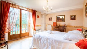 Une chambre à coucher avec un grand lit, une commode en bois, un miroir et un lustre.
