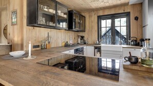 A modern kitchen with wooden cabinetry, a large window, and a central island with a black countertop. - 5 bedroom nice home in Nexø (Nexø)