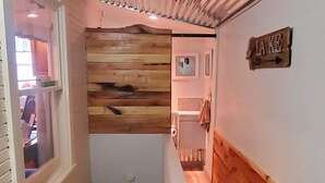 A narrow hallway with wooden paneling, a white door, and a sign that reads "LAKE". - Buckeye Bungalow charming and cozy cottage, close to everything  (Port Clinton)