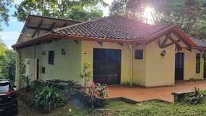 Um edifício de dois andares com telhado de telhas e área de entrada com piso de tijolos.