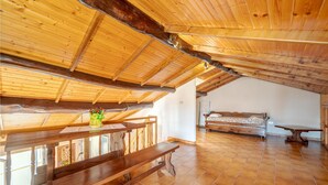 A spacious attic room with a wooden ceiling, a wooden bed, a bench, and a table with a vase of flowers. - 2 bedroom gorgeous apartment in Camogli (Camogli)