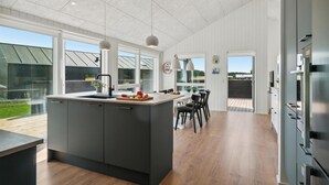 A modern kitchen with a central island, large windows, and a view of the outdoors. - Cozy home in Grenaa with kitchen (Grenaa)