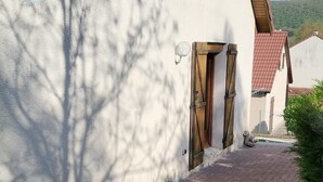 A building with a paved driveway, wooden shutters on the windows, and a clear sky. - Pro home (Besançon)