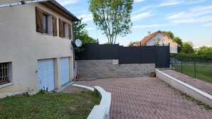 A residential property with a paved driveway, a garage, a satellite dish, and a black fence. - Pro home (Besançon)