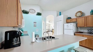 A kitchen with a central island, wooden cabinets, a coffee maker, a sink, and a refrigerator.