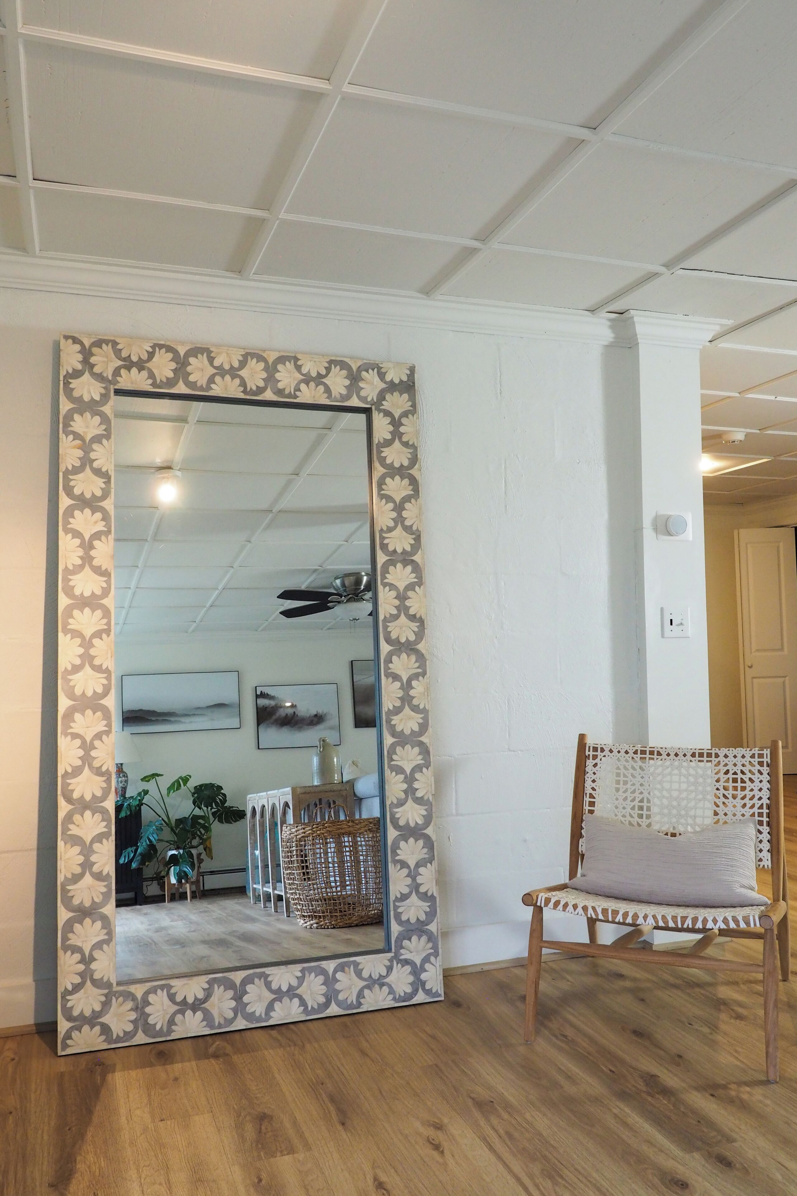 A room with a large mirror, a wicker chair, and a ceiling fan.