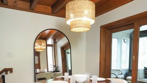 Un coin repas avec une table en bois, des chaises blanches et un lustre.