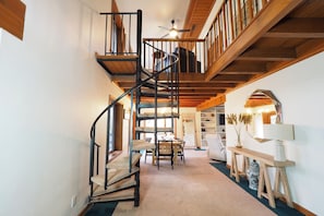 A spiral staircase in a room with a dining area and a console table.