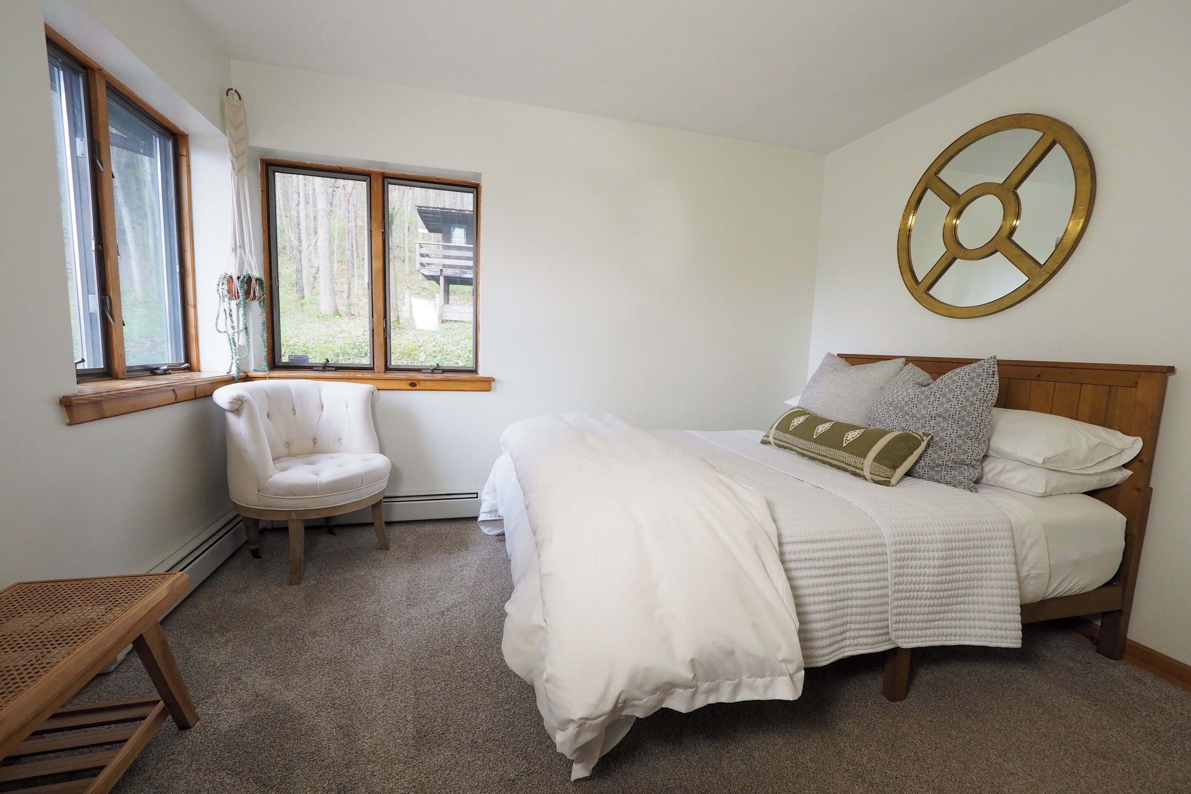 A bedroom with a bed, a chair, a window, and a wall decoration.