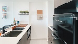 Eine moderne Küche mit einem schwarzen Galanz-Kühlschrank, einem eingebauten Geschirrspüler und einer Arbeitsplatte mit Spüle und Weinglas.