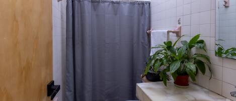 A bathroom with a shower curtain, toilet, sink, and potted plants.