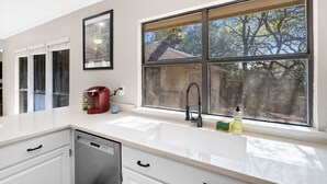 A modern kitchen with a large window, a dishwasher, and a coffee maker on the counter.
