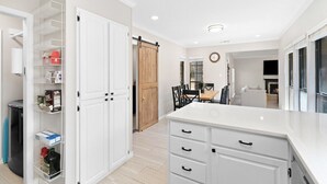 A modern kitchen with white cabinetry, a central island, and a sliding barn door.