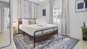 A bedroom with a bed, a ceiling fan, a window with curtains, and a potted plant. - Spacious Designed House -Palm Wave Stays (West Palm Beach)