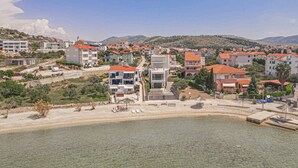 Uma cidade costeira com edifícios modernos, uma praia e montanhas ao fundo.