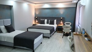 Habitación de hotel con dos camas, un escritorio con silla, una cafetera y una botella de agua.