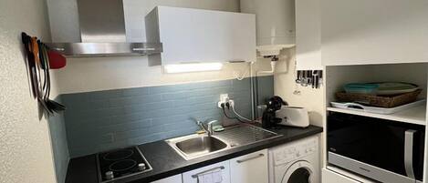 A compact kitchen with a sink, stove, and washing machine.
