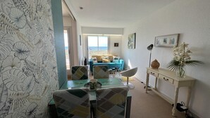 Un coin repas avec une table et des chaises, un canapé en arrière-plan et une vue sur la mer.