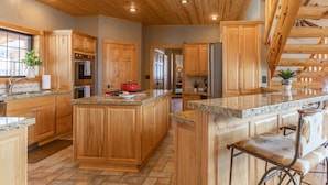 A spacious kitchen with wooden cabinets, granite countertops, and a central island. - MAJESTIC VIEWS | Family Lodge | Large Deck (Star Valley Ranch)