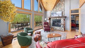 A spacious living area with a fireplace, large windows, and a dining area. - MAJESTIC VIEWS | Family Lodge | Large Deck (Star Valley Ranch)