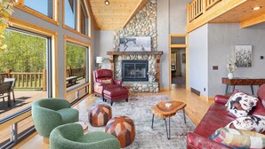 A spacious living area with large windows, a stone fireplace, and a wooden ceiling. - MAJESTIC VIEWS | Family Lodge | Large Deck (Star Valley Ranch)
