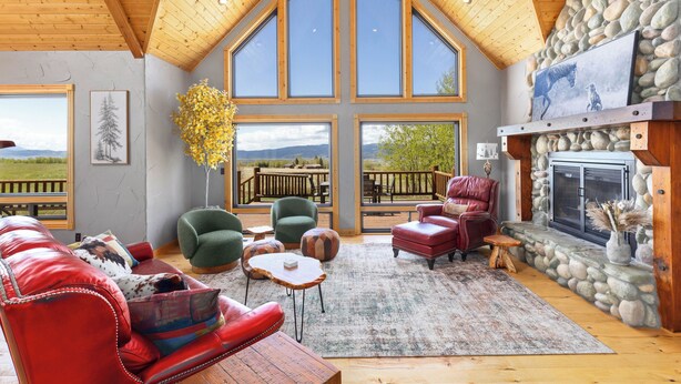 A spacious living room with a stone fireplace, large windows, and a cozy seating area. - MAJESTIC VIEWS | Family Lodge | Large Deck (Star Valley Ranch)