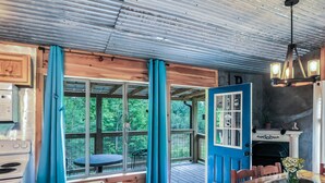 A rustic cabin interior with a wooden deck, a dining table, and a fireplace. - Romantic Red River Gorge Cabin w/ Hot Tub, Pond Views & Dog Friendly (Frenchburg)