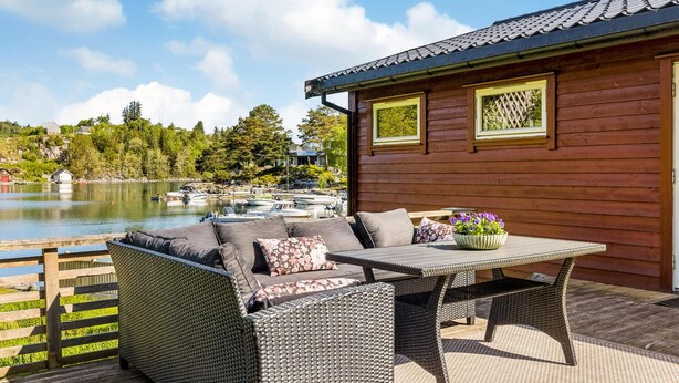 A wooden cabin with a deck, a table, and a sofa. - 3 bedroom awesome home in Sveio (Sveio)