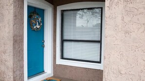 A blue door with a wreath, a window with blinds, and a welcome mat.