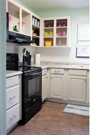 A kitchen with white cabinets, a black stove, and a countertop.