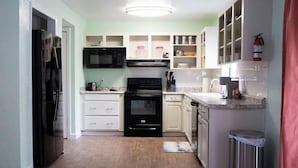 A compact kitchen with a refrigerator, microwave, oven, and dishwasher.